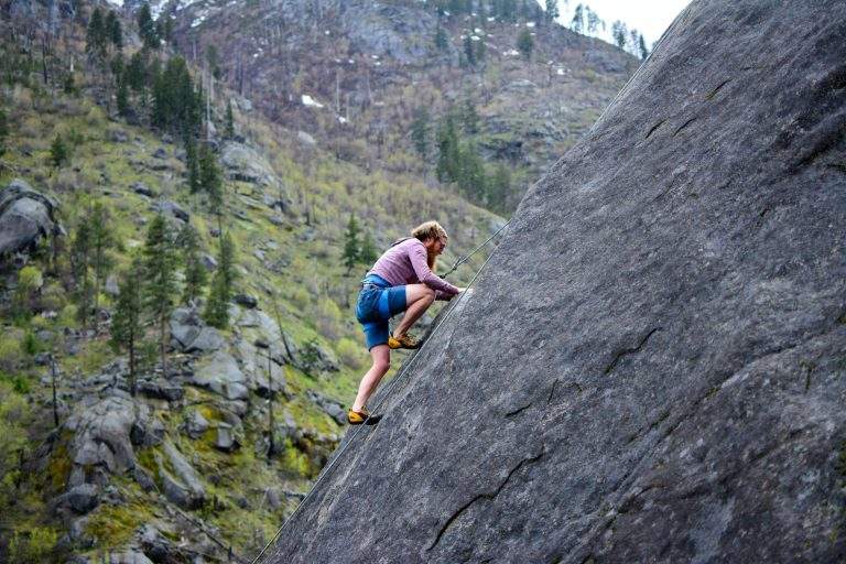 Person climbing a mountain with a sunrise, representing the path to lifelong success through positive thinking.