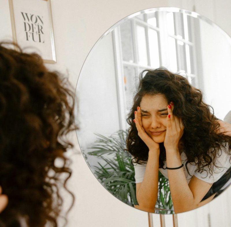 Upset woman looking in mirror