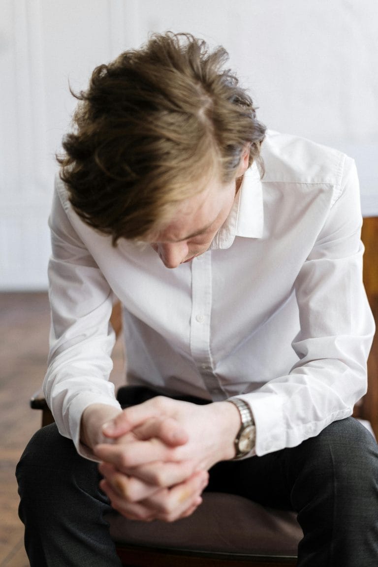 A distressed man holding his head, representing the internal conflict of abusive husbands struggling with self-esteem.