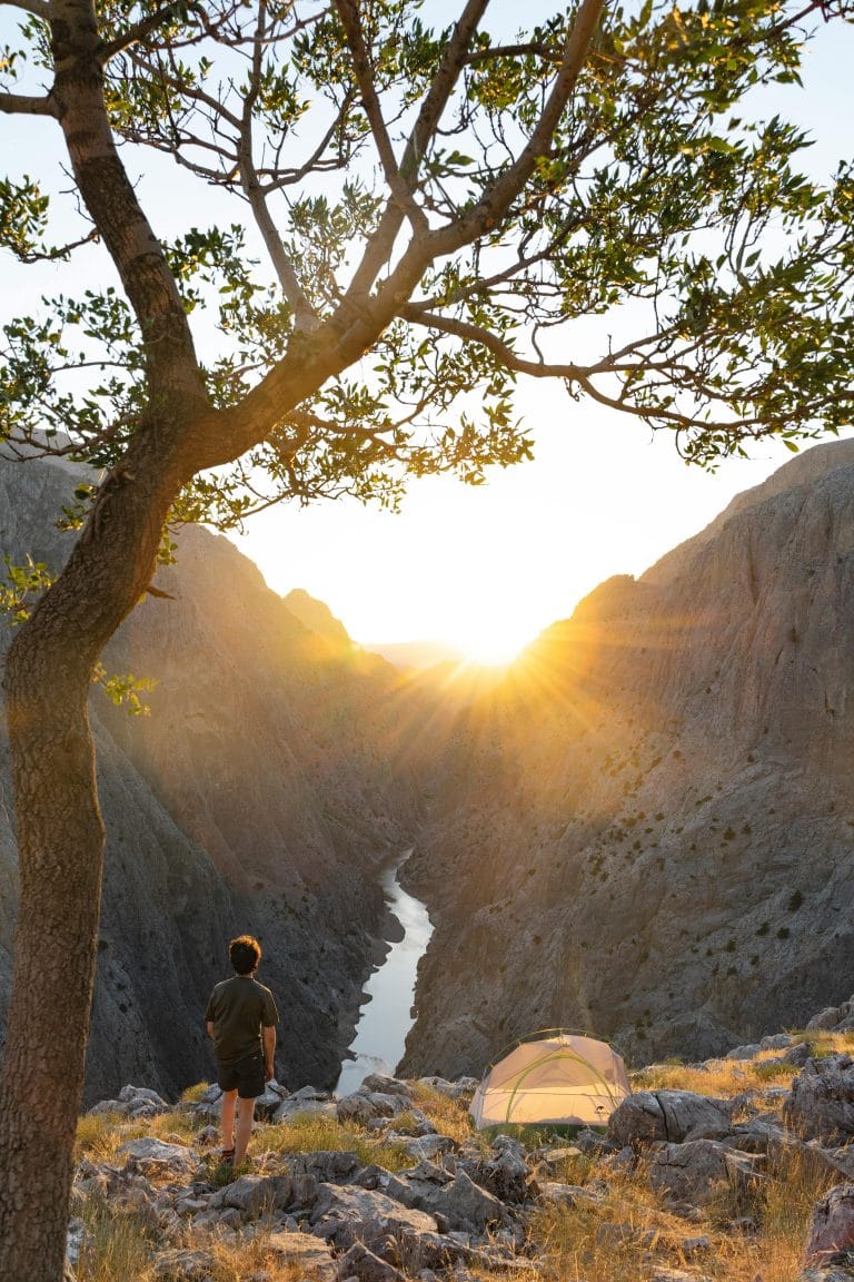 Person standing on mountain at sunrise, living purposefully