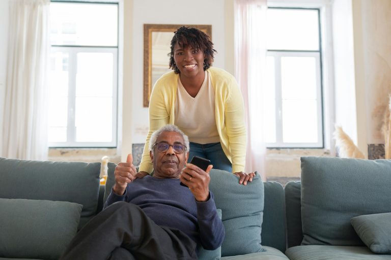 A caregiver offering support by holding hands with an elderly person.