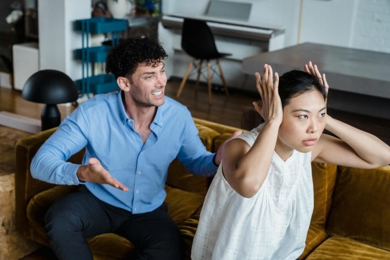 A couple sitting apart with tense expressions, symbolizing the psychological impact of false accusations in relationships.