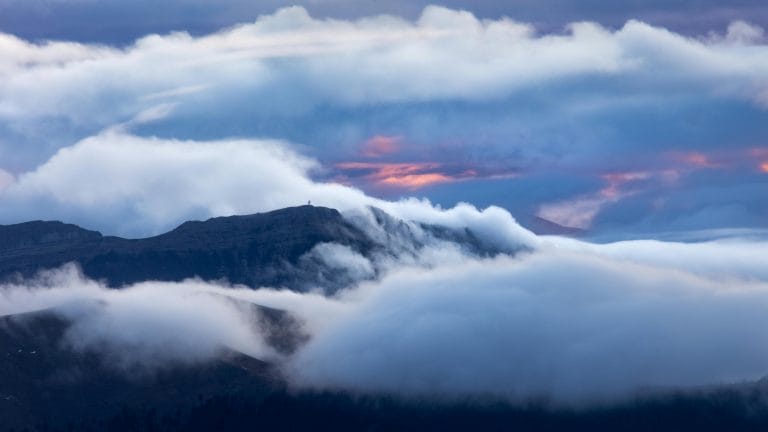 Light breaking through clouds over a calm landscape, symbolizing hope during grief.