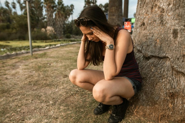 Person reflecting under a tree, symbolizing reactive depression and recovery.